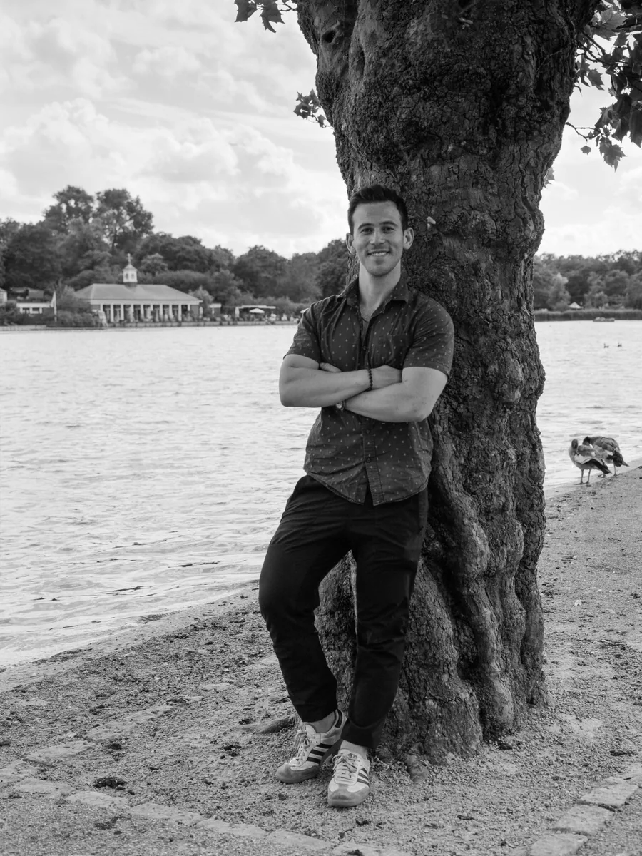 Jake Present standing beside a tree by a lake